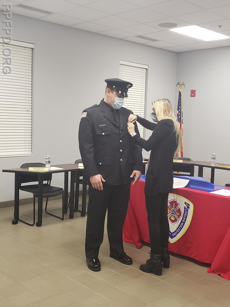 FF/PM Nicholas Hooten's fiancé, Nicole  pins his badge on during the swearing-in ceremony on March 9, 2021.
